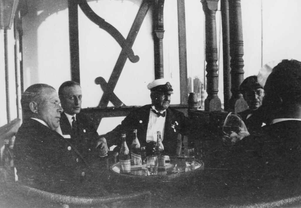 Johan Erik Carlsson (1870–1935) – “Glas-Kalle” – i mitten med skepparmössa, fotograferad i Sandhamn. Redan under sin egen tid var han en legend inom svensk segling. Foto: Sjöhistoriska museet