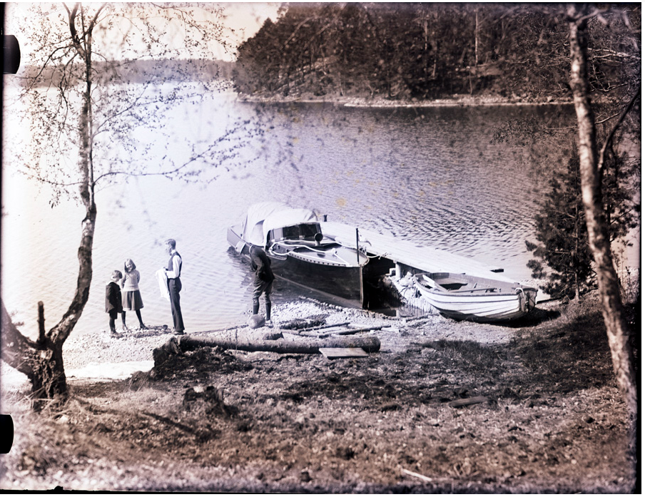 Ett tidigt ögonblick ur Rakets historia: den slanka motorbåten ligger förtöjd vid en strand, med familj och sällskap samlade i strandkanten – en påminnelse om hur dessa båtar användes som vardagens och sommarens färdmedel. Foto: Loris Charter