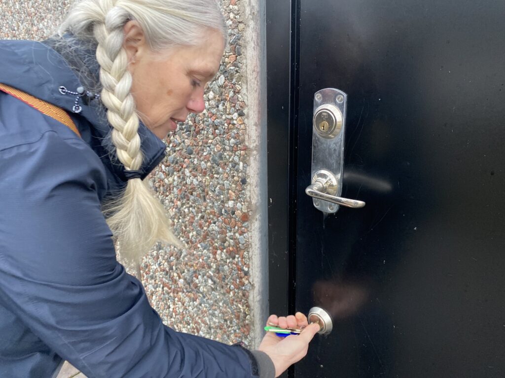 Intendenten Eva Berglund Thörnblom vrider om nyckeln och låser den tunga dörren till magasinet på Rindö, där Sjöhistoriska museet förvarar delar av sina samlingar – bland annat tre Petterssonbåtar: Plurr, Wiking X och en klassisk Petterssonbåt utan namn. Foto: Martin Prieto Beaulieu