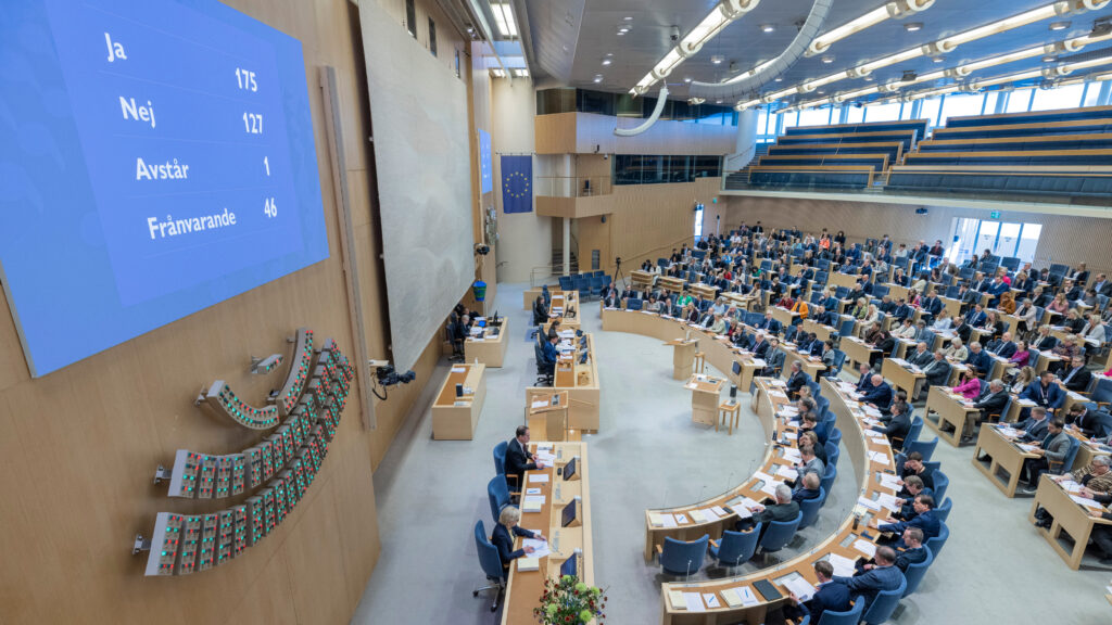 Kammaren under votering. Voteringstavlan visar hur varje ledamot röstat; grön lampa för "ja", röd "nej" och gul "avstår". Foto: Melker Dahlstrand/Sveriges riksdag