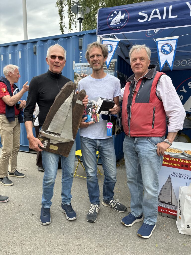 Janne och Max Nystedt vann Peter Norlin Memorial Classic 2026 med SK 30 Pani S-163 från 1937. Här tar de emot priset från Sail Yacht Societys ordförande Ulf Aronsson. Foto: Martin Prieto Beaulieu